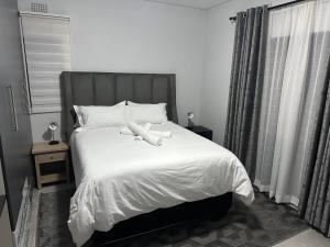 una camera da letto con letto, lenzuola e cuscini bianchi di Mountain Drive Apartments a Mbabane