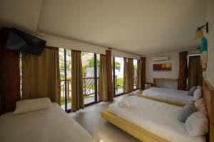 two beds in a room with large windows at Kabañas Ojo de Agua in Puerto Morelos