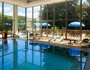 einen Pool mit Stühlen und Sonnenschirmen in einem Gebäude in der Unterkunft Hotel U Zámečku Cihelny in Karlsbad