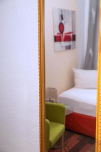 a mirror in a room with a bed and a green chair at Rothenberger Plauen in Plauen