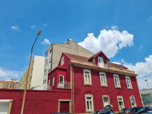 een rood gebouw op een straat met auto's aan de voorkant bij Vintage Beach House in Matosinhos