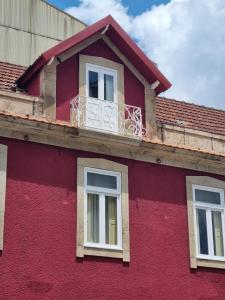 een rood gebouw met een balkon erboven bij Vintage Beach House in Matosinhos