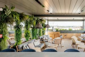 a living room with couches and chairs and plants at Grand Hotel Bellevue - Grand Place in Lille