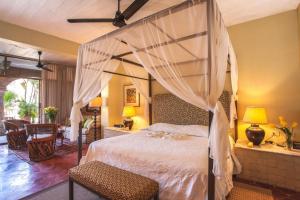 a bedroom with a canopy bed and a living room at Quinta Maria Cortez in Puerto Vallarta