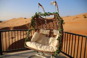 a swing chair sitting on a balcony in the desert at Oman desert private camp in Shāhiq