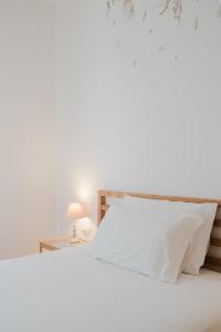 einem Bett mit weißer Bettwäsche und einem Tisch mit einer Lampe in der Unterkunft B&B La finestra sul porto in Porto Torres