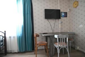 a room with a table and a television on a wall at Babulya House in Gyumri