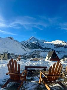 2 Stühle und ein Picknicktisch im Schnee mit Bergen in der Unterkunft Hillside Kazbegi in Kazbegi