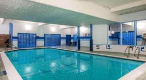 a large swimming pool with blue water in a building at Howard Johnson Hotel by Wyndham Victoria in Victoria