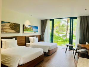 ファンティエットにあるThe Vista Beach Resort Phan Thiếtのベッド2台と窓が備わるホテルルームです。