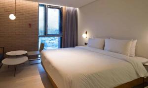 a bedroom with a large white bed and a window at Cont Hotel in Busan