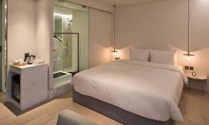 a bedroom with a large white bed and a shower at Cont Hotel in Busan