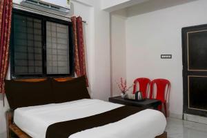 um quarto com uma cama e 2 cadeiras vermelhas em Super Hotel O Manjari Road em Pune