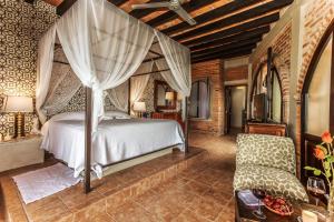 a bedroom with a canopy bed and a chair at Quinta Maria Cortez in Puerto Vallarta