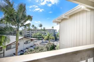 - un balcon avec vue sur un bâtiment et des palmiers dans l'établissement Kona Bali Kai, à Kailua-Kona