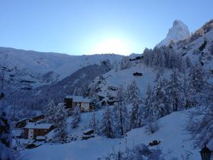 een met sneeuw bedekte berg met bomen en een gebouw bij Chalet Kolibri in Zermatt