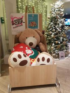 Un ours en peluche assis dans une boîte à côté d'un arbre de Noël dans l'établissement Novotel Dijon Sud, à Dijon