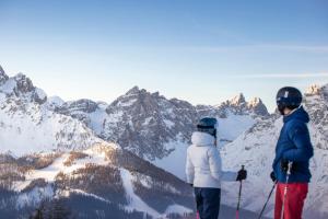 dos personas de pie en la cima de una montaña cubierta de nieve en Hotel Gratschwirt, en Dobbiaco