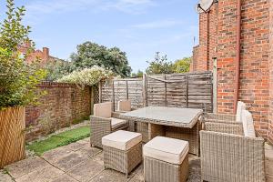 eine Terrasse mit einem Tisch, Stühlen und einer Ziegelwand in der Unterkunft Beautiful Three-Bedroom House in Richmond in Richmond upon Thames