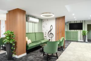 une salle d'attente avec un canapé vert et des chaises dans l'établissement Aranyhomok Business-City-Wellness Hotel, à Kecskemét