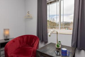 une chaise rouge et une table dans une chambre avec fenêtre dans l'établissement RiverWalk Inn, à Pagosa Springs