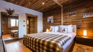 ein Schlafzimmer mit einem Bett in einem Zimmer mit Holzwänden in der Unterkunft Chalet de ski avec piscine - Megève in Megève