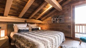 ein Schlafzimmer mit einem Bett in einer Holzhütte in der Unterkunft Chalet de ski avec piscine - Megève in Megève