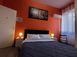 a bedroom with a bed with an orange wall at Adriatic Room 50 m dalla stazione Ferroviaria di Ciampino e dalla navetta aeroportuale in Ciampino