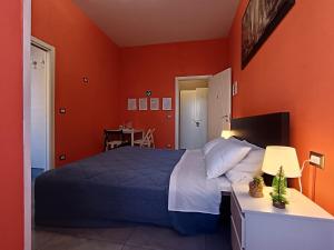 a bedroom with a bed and an orange wall at Adriatic Room 50 m dalla stazione Ferroviaria di Ciampino e dalla navetta aeroportuale in Ciampino