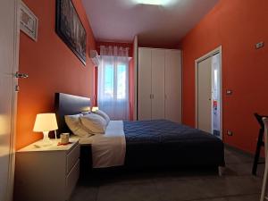 a bedroom with orange walls and a bed and a lamp at Adriatic Room 50 m dalla stazione Ferroviaria di Ciampino e dalla navetta aeroportuale in Ciampino