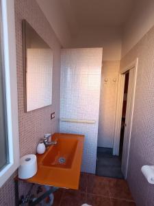 a bathroom with an orange sink and a mirror at Adriatic Room 50 m dalla stazione Ferroviaria di Ciampino e dalla navetta aeroportuale in Ciampino