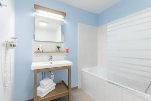 y baño blanco con bañera, lavamanos y bañera. en Appart'City Confort Niort Centre, en Niort