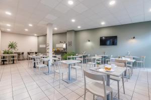 un restaurante con mesas y sillas y TV en la pared en Appart'City Confort Niort Centre, en Niort