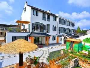 a large white building with a straw umbrella at Shanghai Chuxin Moshe B&B Disney Store in Shanghai