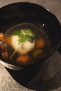 una ciotola nera di zuppa con verdure dentro di YORUYA a Kurashiki