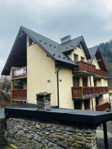 una casa con un tetto nero in cima a un muro di pietra di Nad Grajcarkiem a Szczawnica