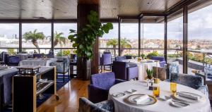 un restaurante con mesas y sillas y vistas a la ciudad en Altis Grand Hotel, en Lisboa