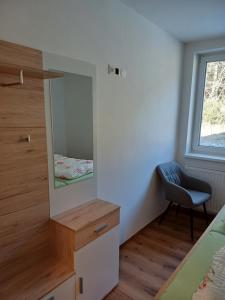 ein Schlafzimmer mit einem Spiegel und einem Stuhl in der Unterkunft Appartements Dorner in Steinhaus am Semmering