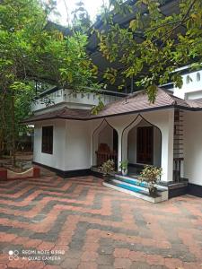 ein kleines weißes Haus mit einer Backsteinterrasse in der Unterkunft Delma Holidays Varkala in Varkala