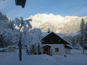 une maison recouverte de neige avec des montagnes en arrière-plan dans l'établissement Ferienhaus Schwarzenbacher, à Lungötz