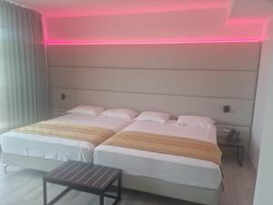 2 Betten in einem Zimmer mit rosafarbener Beleuchtung in der Unterkunft HOTEL VENICE BEACH HVB 34 Lifestyle 4 Superior in Bibione