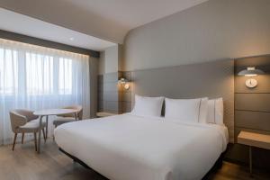 a bedroom with a large white bed and a table at AC Hotel Carlton Madrid by Marriott in Madrid