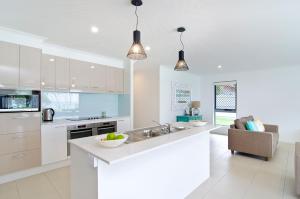 una cucina bianca con lavandino e bancone di Sentosa on Tugun - Beachfront 5 Bedroom a Gold Coast