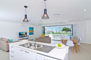 una cucina e un soggiorno con lavandino e tavolo di Sentosa on Tugun - Beachfront 5 Bedroom a Gold Coast