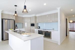 una cucina con armadi bianchi e piano di lavoro bianco di Sentosa on Tugun - Beachfront 5 Bedroom a Gold Coast