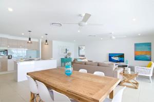 una cucina e un soggiorno con tavolo e sedie in legno di Sentosa on Tugun - Beachfront 5 Bedroom a Gold Coast