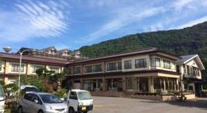 un gran edificio con coches estacionados en un estacionamiento en Towadako Lakeside Hotel, en Towada