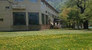 un edificio con un campo de flores delante de él en Towadako Lakeside Hotel, en Towada