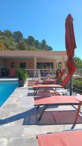 - un groupe de chaises longues et de parasols à côté de la piscine dans l'établissement Les Hauts du Peireguier, à La Motte