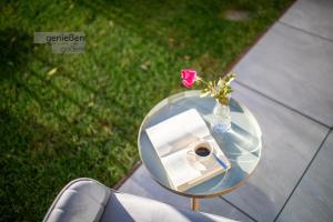 een glazen tafel met een vaas met een roos erin bij Apartments Liana in Postal